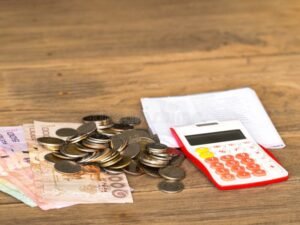 factura con calculadora y monedas sobre mesa