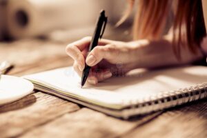 mano escribiendo en cuaderno con boligrafo