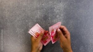 manos contando billetes junto a tarjeta rosa