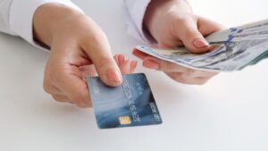 manos sosteniendo billetes y tarjeta bancaria