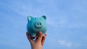 manos sosteniendo una hucha de cerdito azul