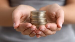 manos sosteniendo una pila de monedas