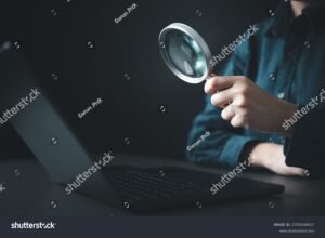 manos usando lupa frente a laptop cerrada