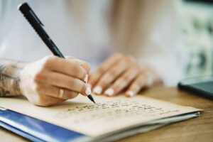 persona escribiendo carta formal en escritorio elegante