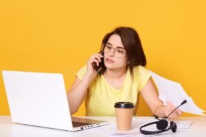 persona hablando por telefono con computadora abierta