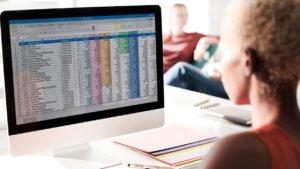 persona trabajando en computadora con hoja de excel abierta