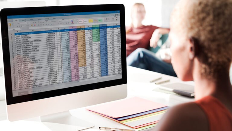 persona trabajando en computadora con hoja de excel abierta