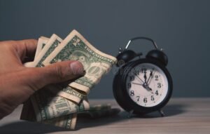 reloj y dinero en mano sobre mesa